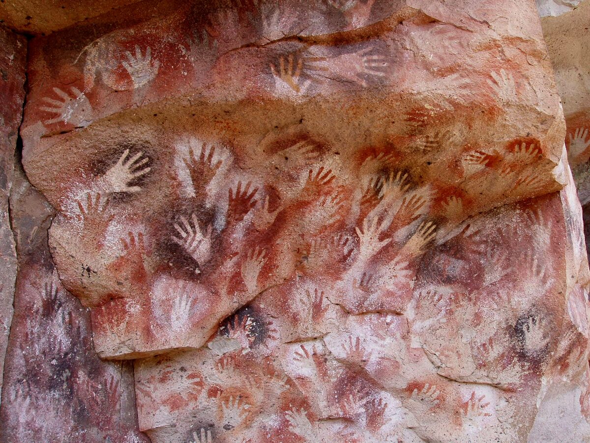 Mains négatives peintes en ocre sur la paroi d'une grotte